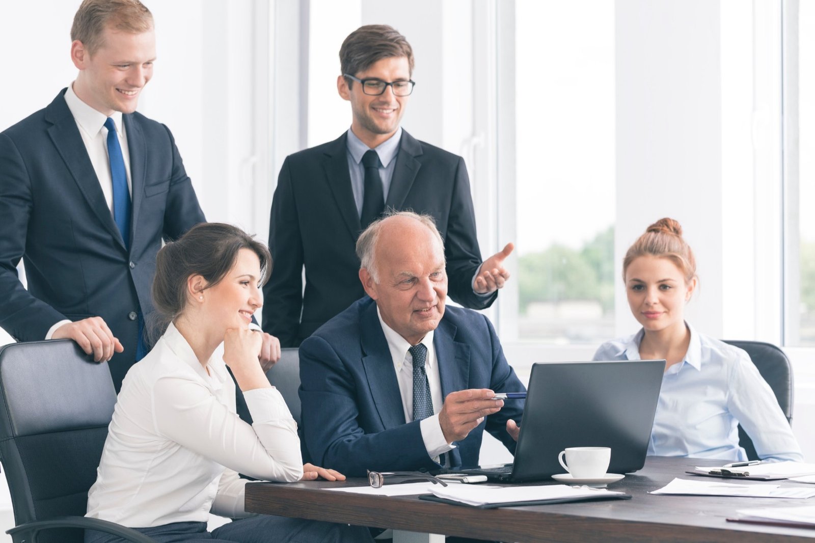 Equipe reunida em torno de um notebook em reunião de trabalho